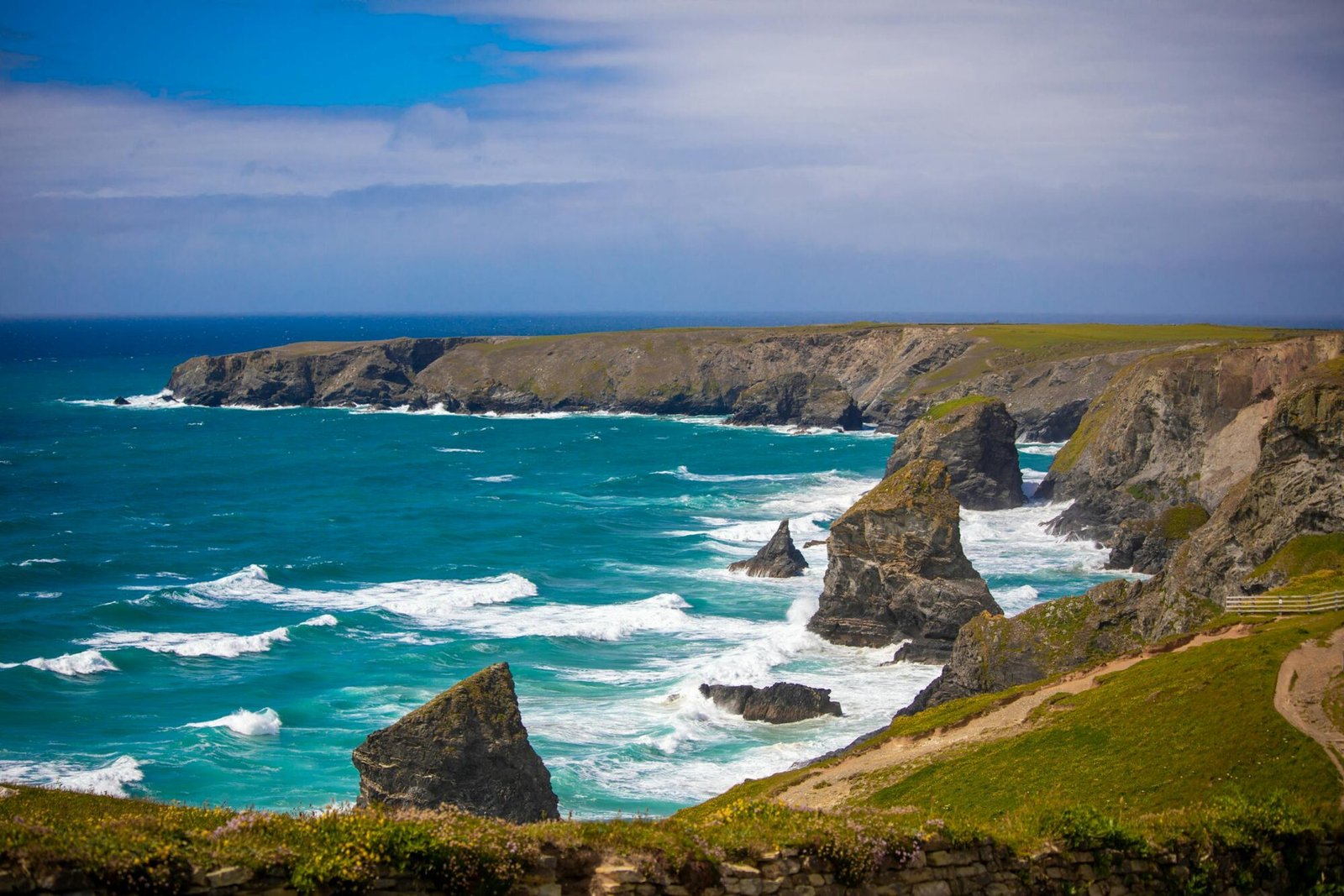 Breathtaking view of rugged coastal cliffs and turquoise ocean waves under a bright, clear sky.